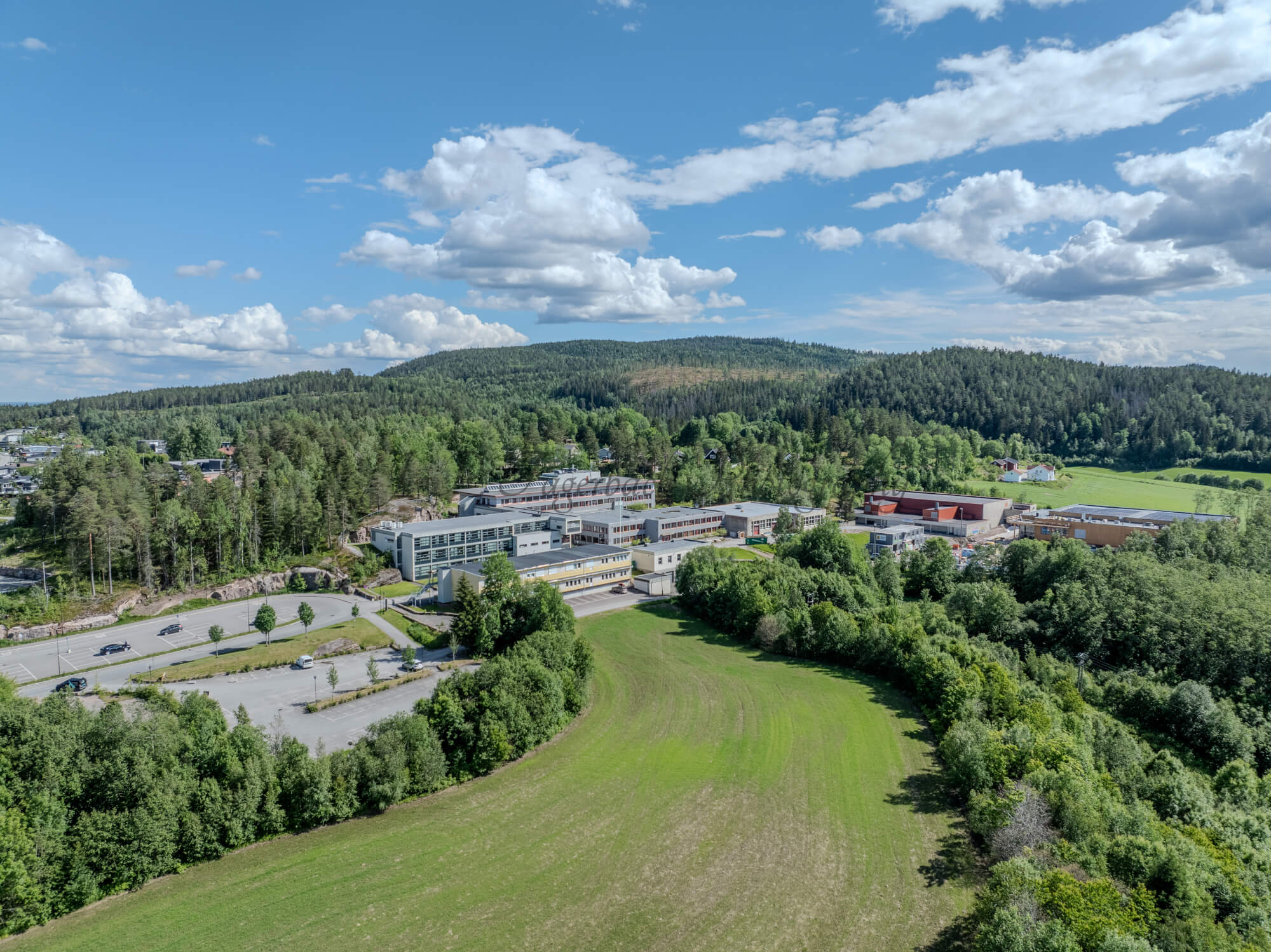 Buildings in a wooded green area under a partially clouded blue sky