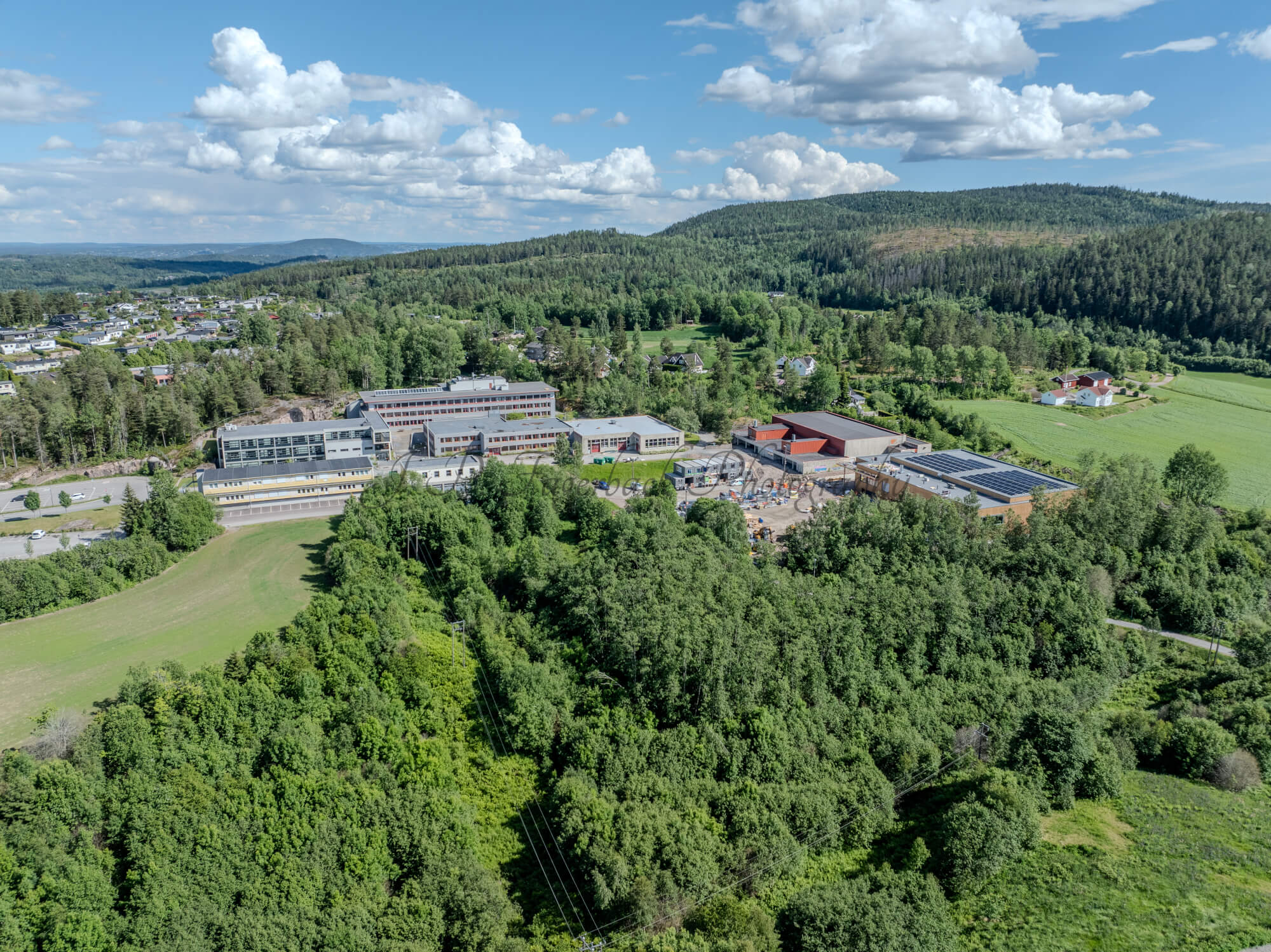 Buildings in a wooded green area under a partially clouded blue sky