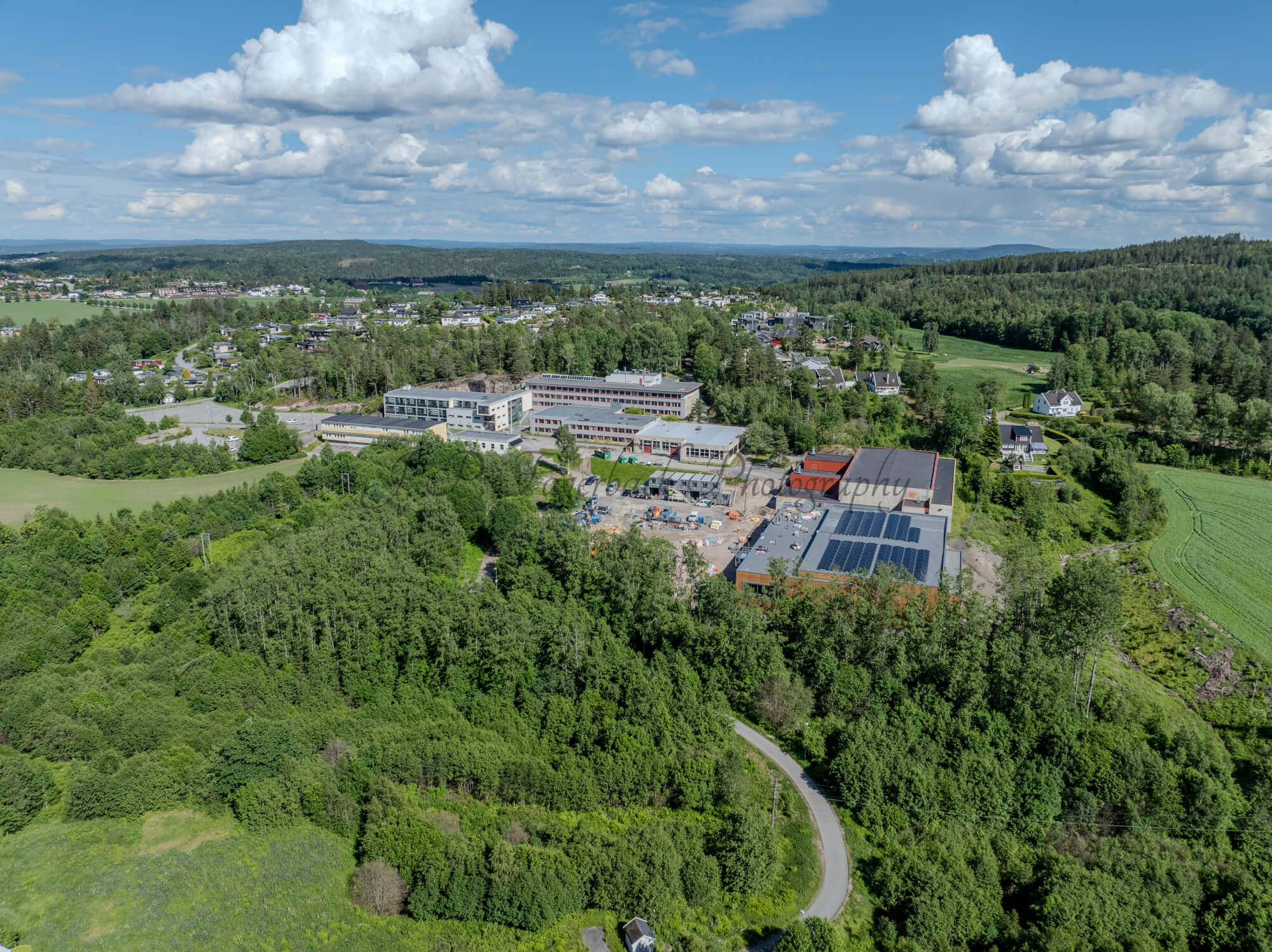 Buildings in a wooded green area under a partially clouded blue sky