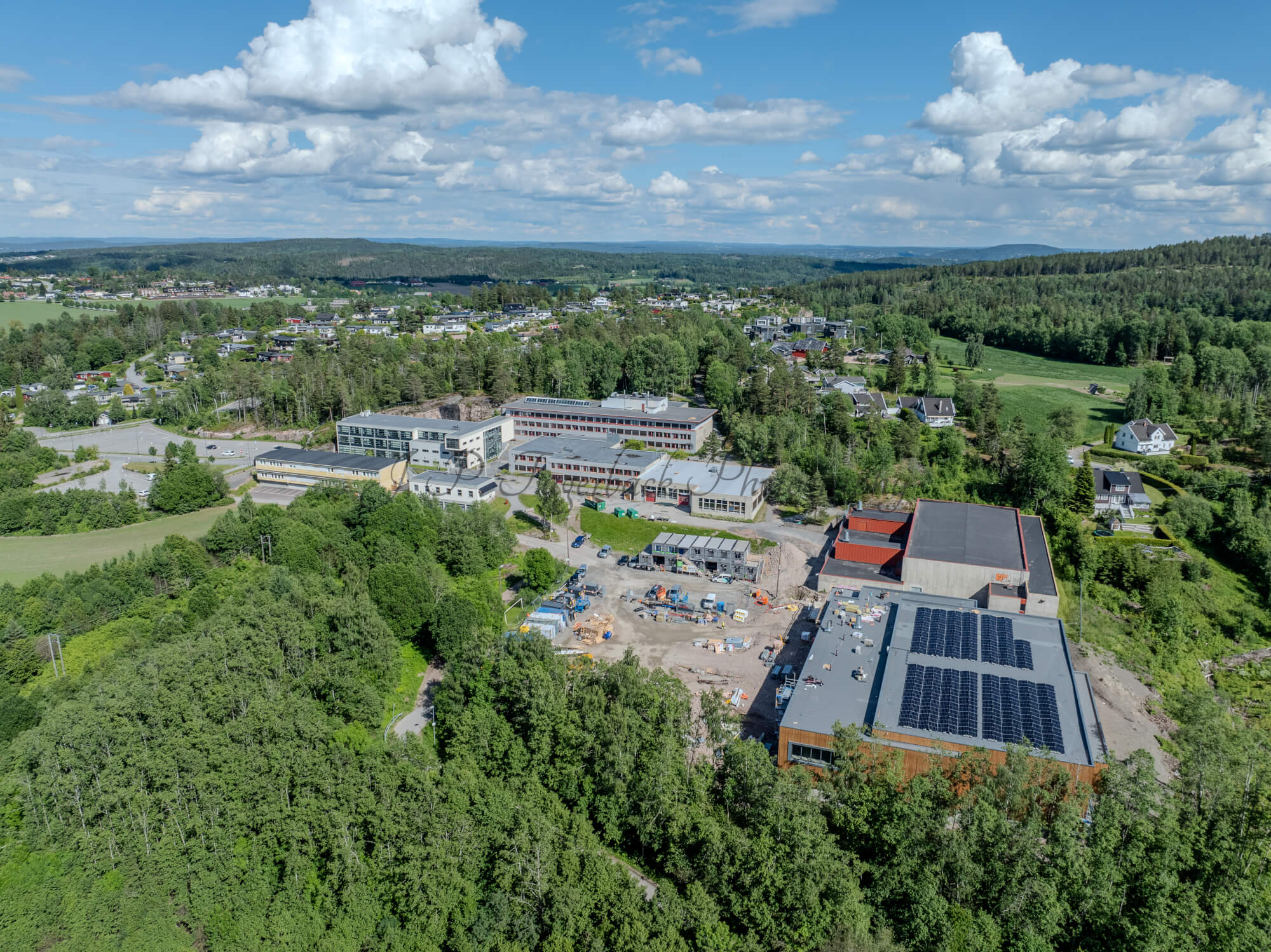 Buildings in a wooded green area under a partially clouded blue sky