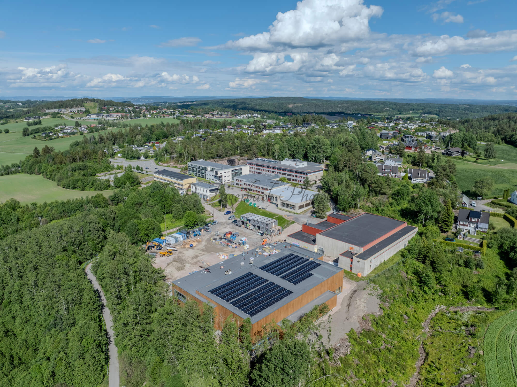 Buildings in a wooded green area under a partially clouded blue sky