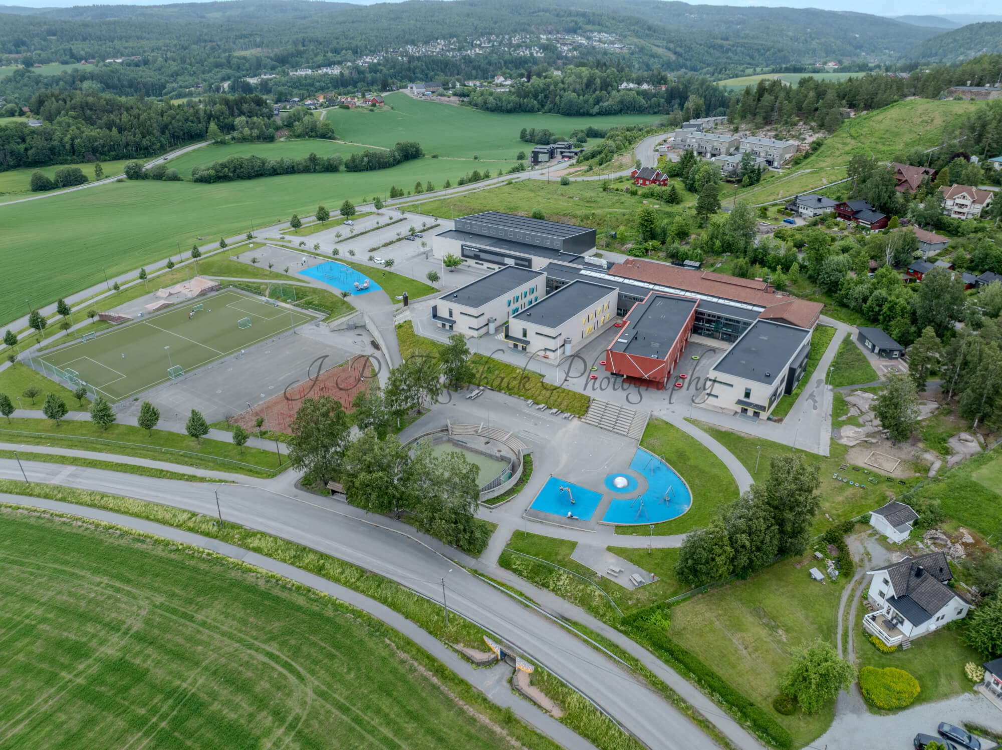 Colorfull school buildings in an are with other houses and green fields