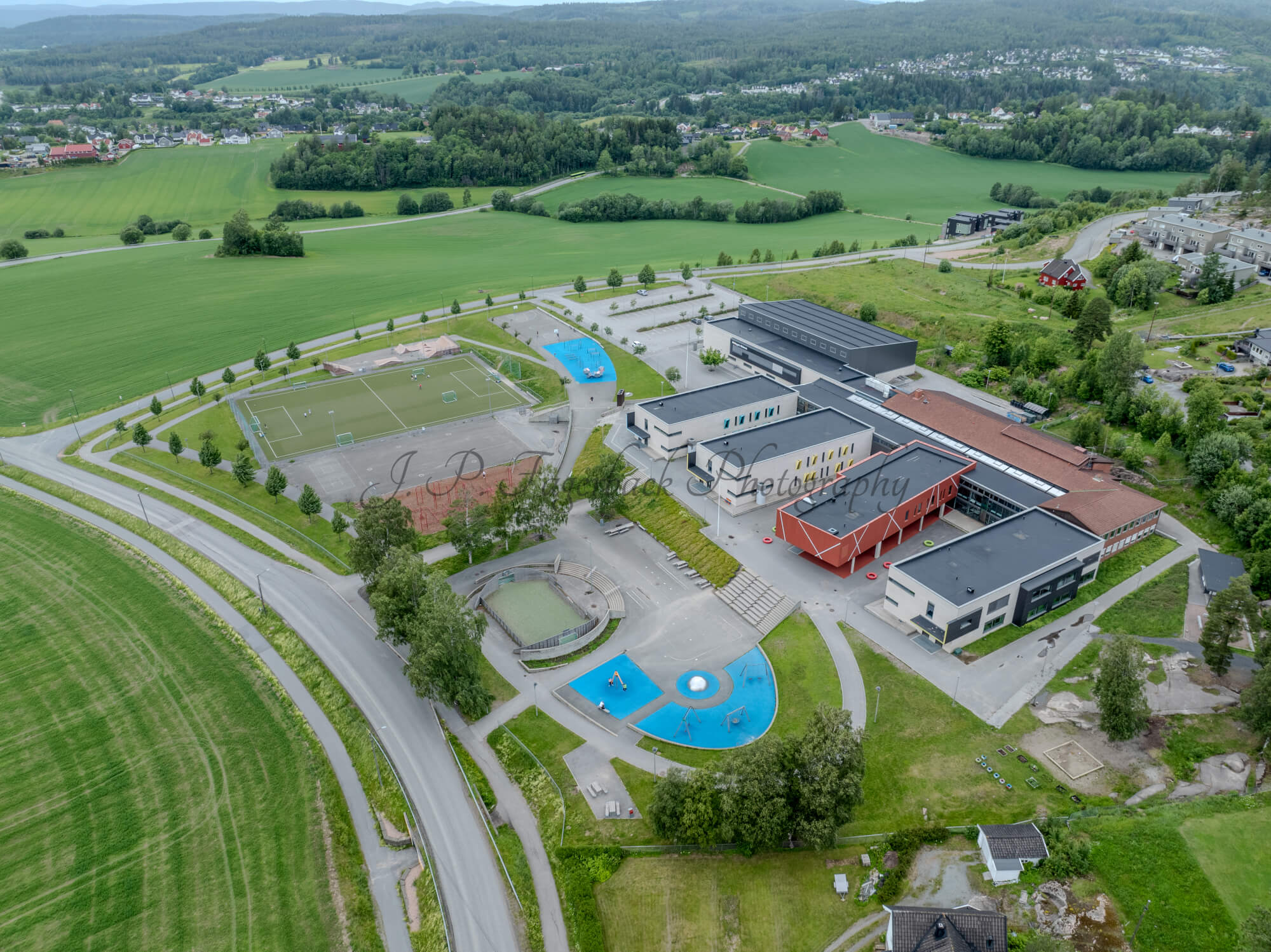 Colorfull school buildings in an are with other houses and green fields