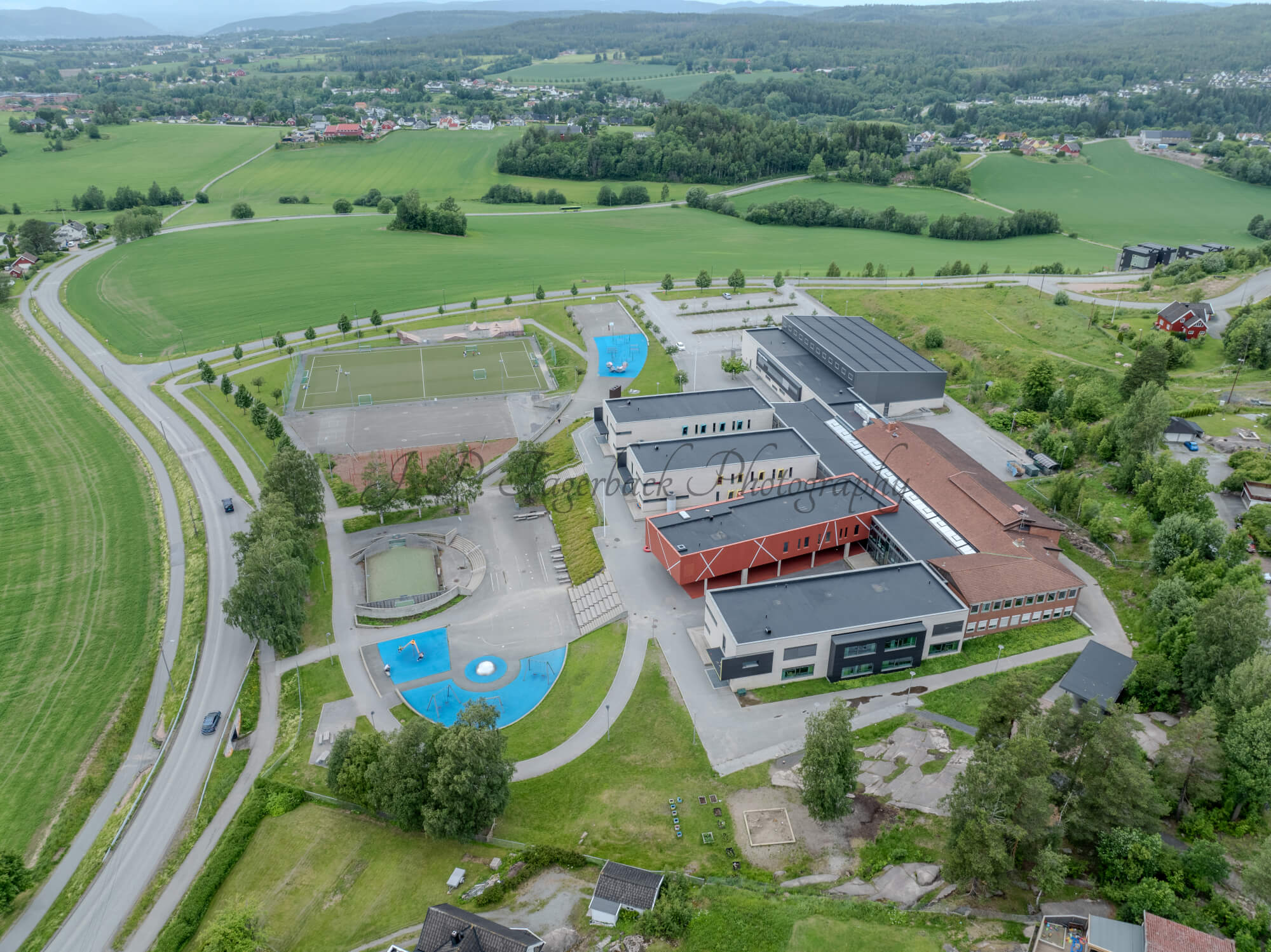 Colorfull school buildings in an are with other houses and green fields