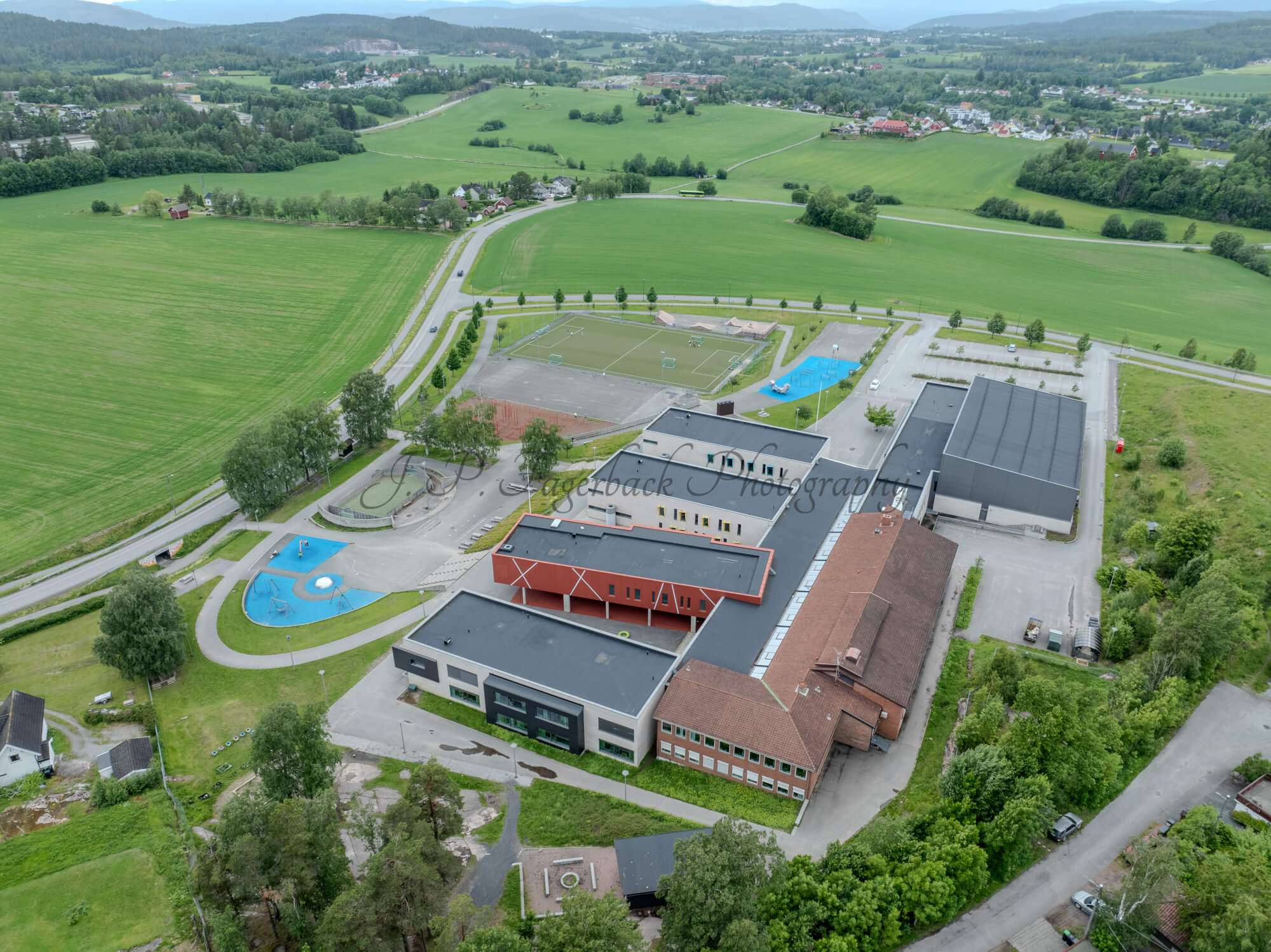 Colorfull school buildings in an are with other houses and green fields