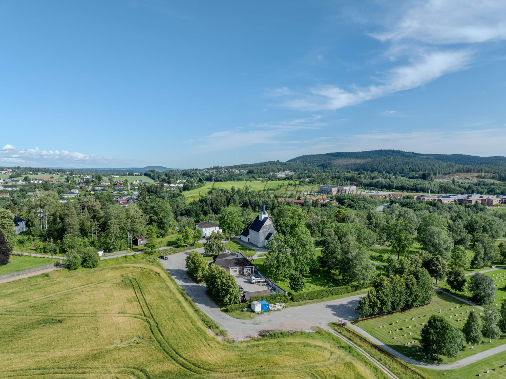 White stone church in background of a green landscape under a blue sky