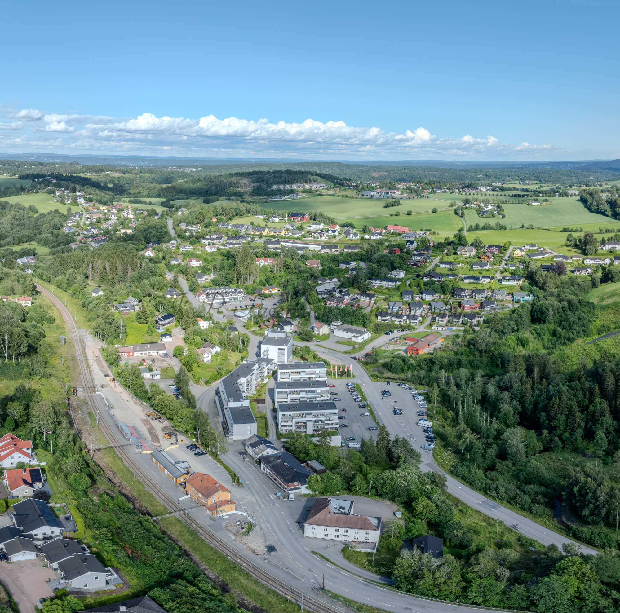 Buildings in a green landscape under a blue sky with small amounts of white clouds
