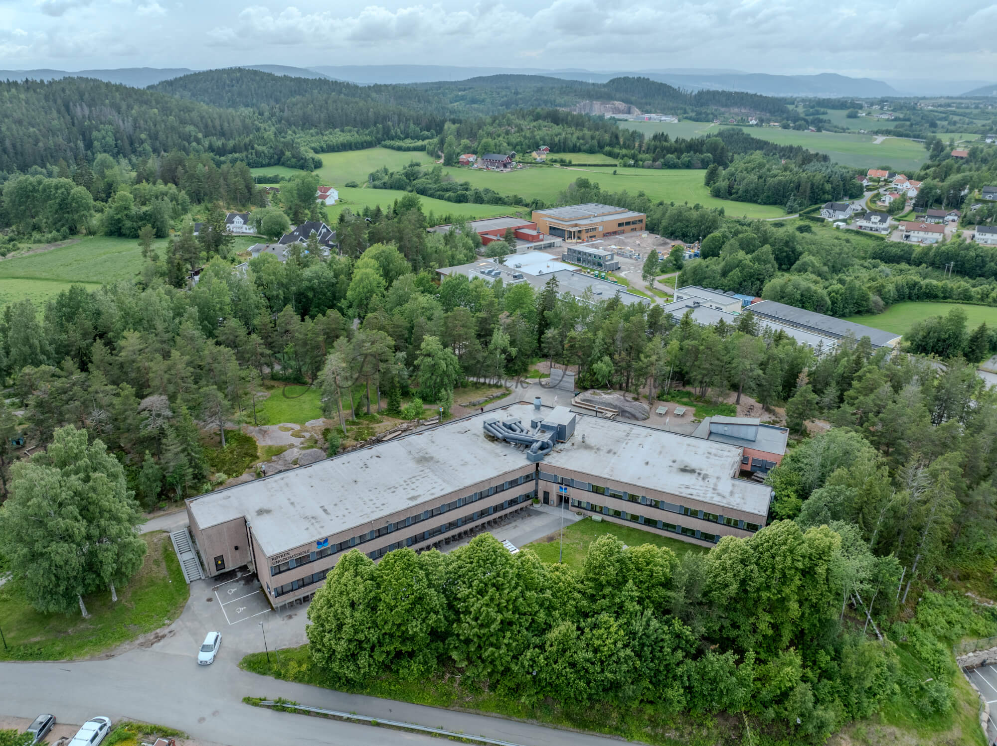Buildings in a wooded green area under a partially clouded blue sky
