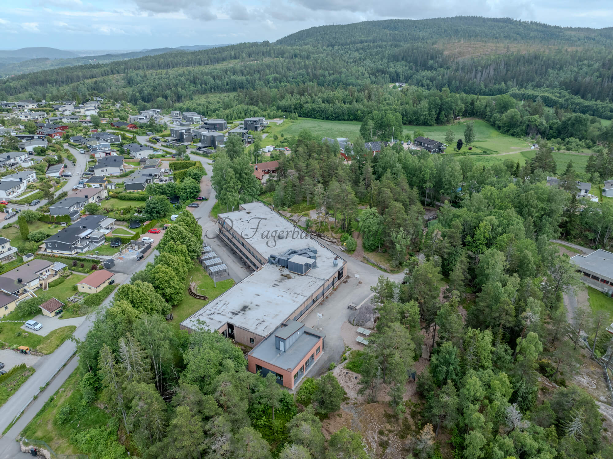 Buildings in a wooded green area under a partially clouded blue sky