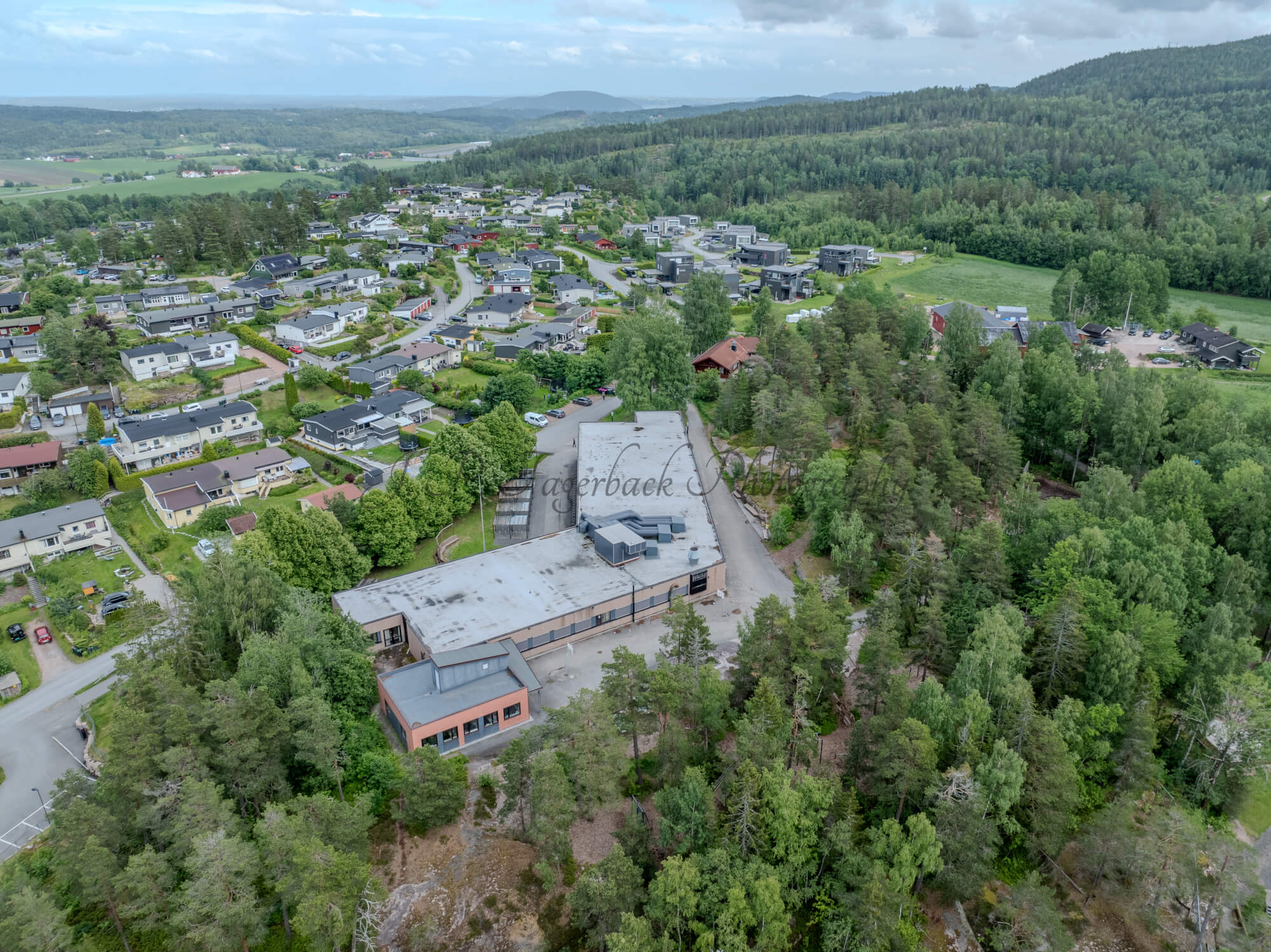 Buildings in a wooded green area under a partially clouded blue sky