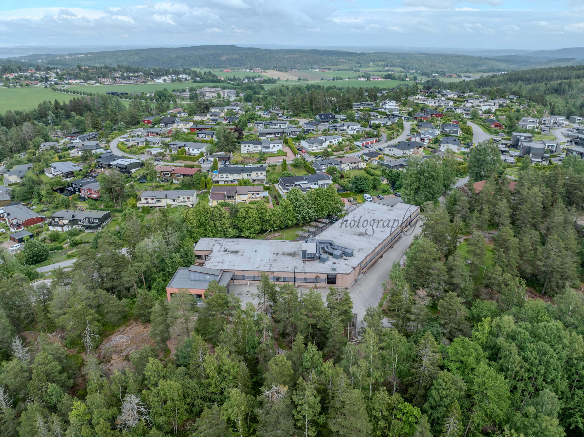 Buildings in a wooded green area under a partially clouded blue sky