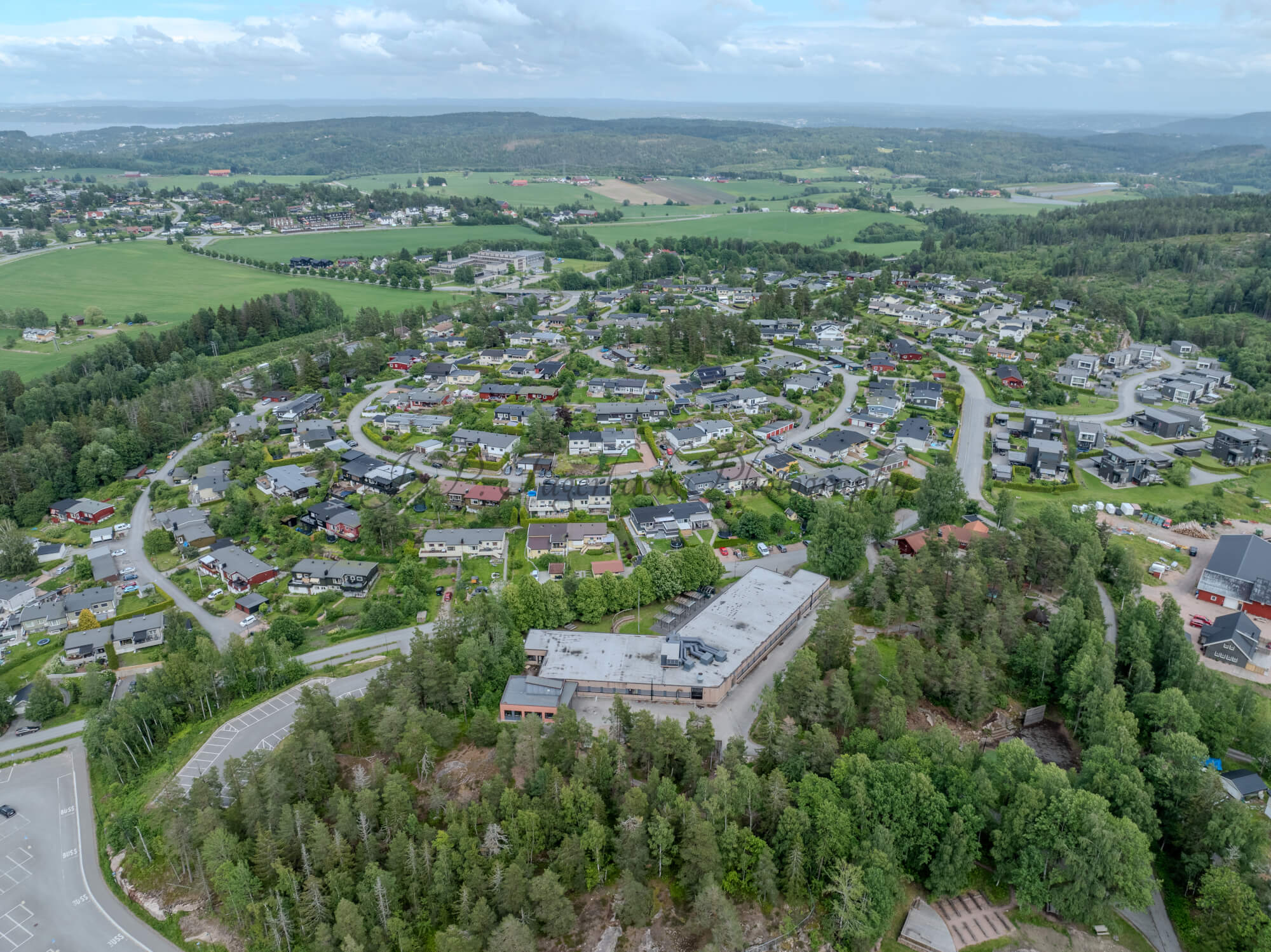 Buildings in a wooded green area under a partially clouded blue sky