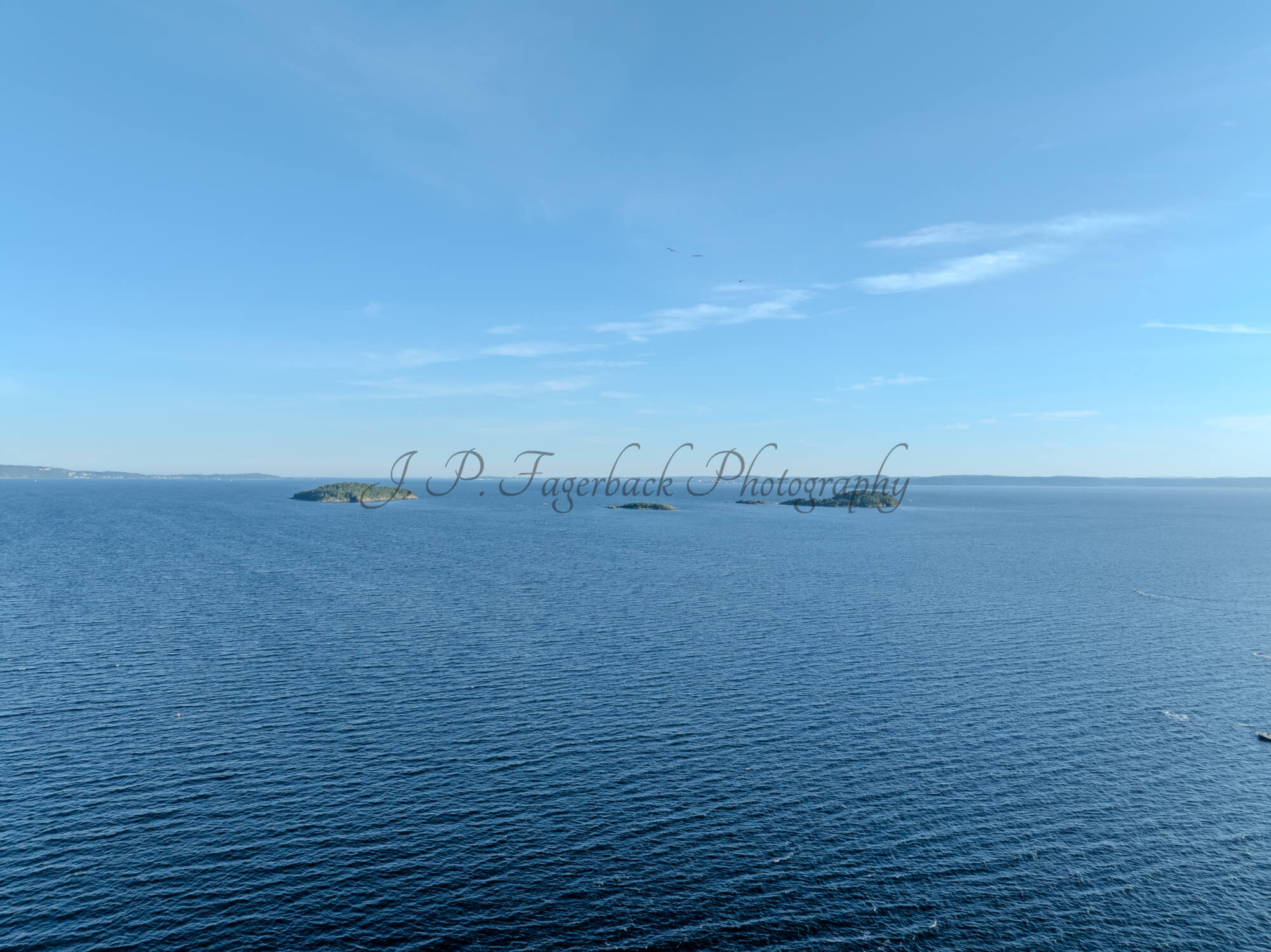 Small islands in a body of blue water under an almost cloudless blue sky