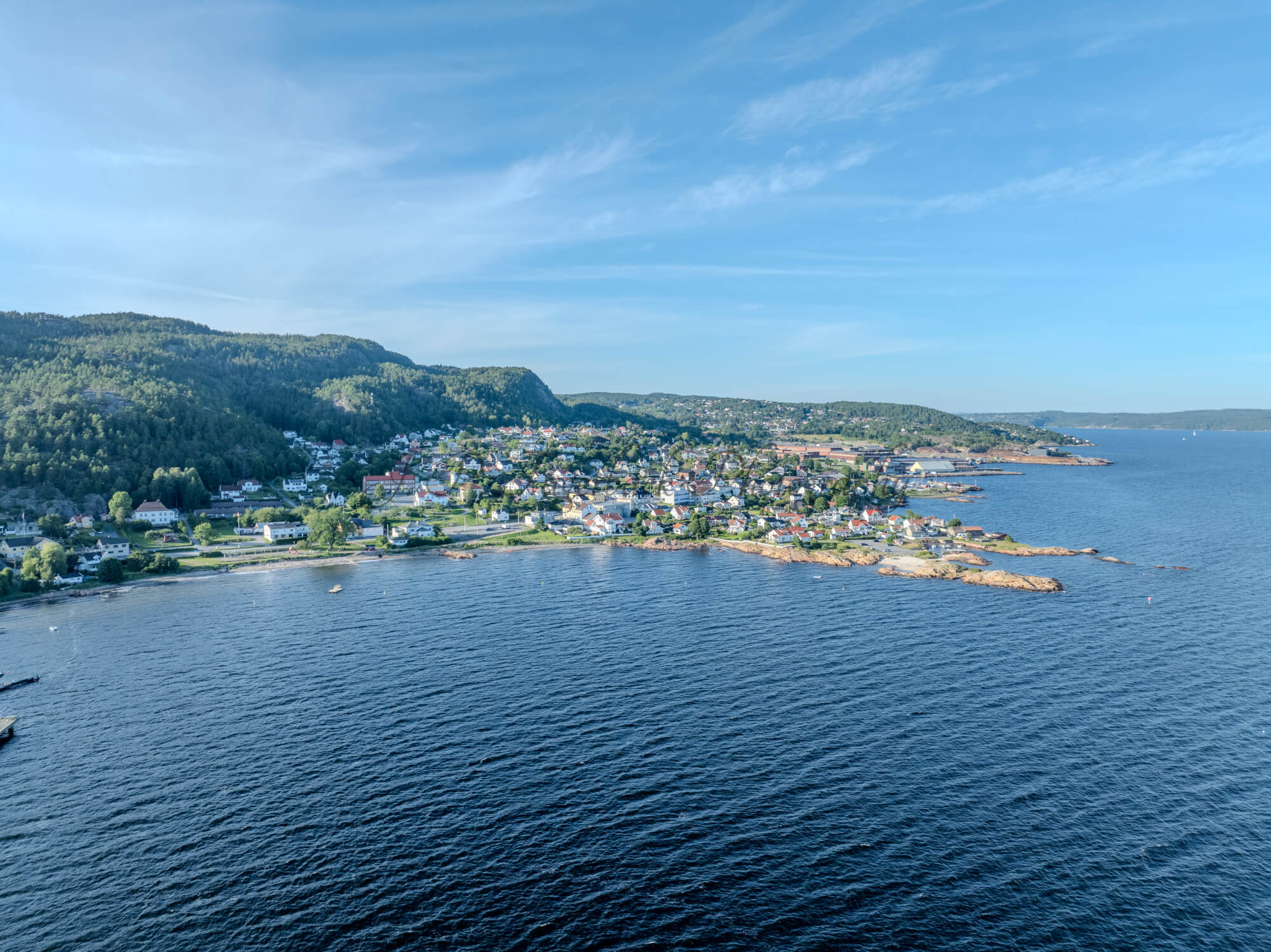 Houses of a town close to a body of water under an almost cloudless sky