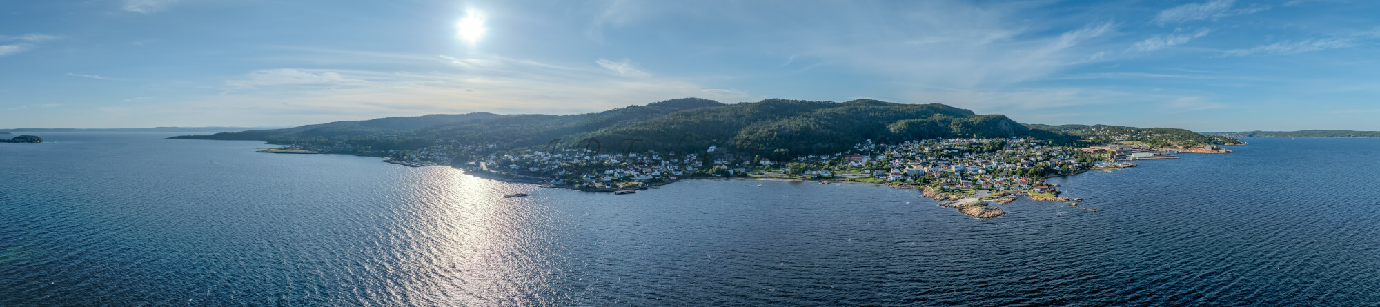 Houses of a town close to a body of water under an almost cloudless sky