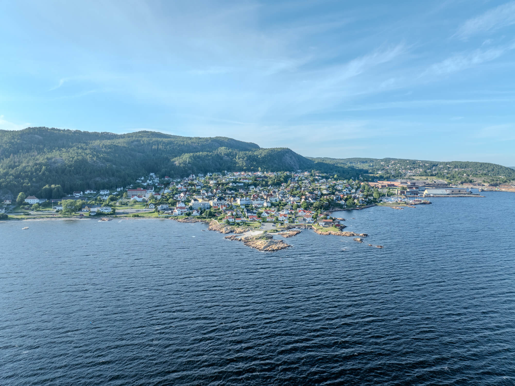 Houses of a town close to a body of water under an almost cloudless sky
