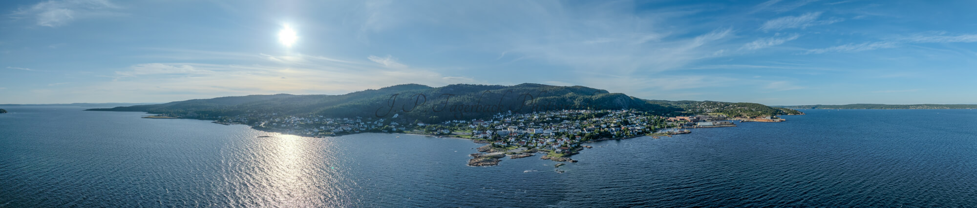 Houses of a town close to a body of water under an almost cloudless sky