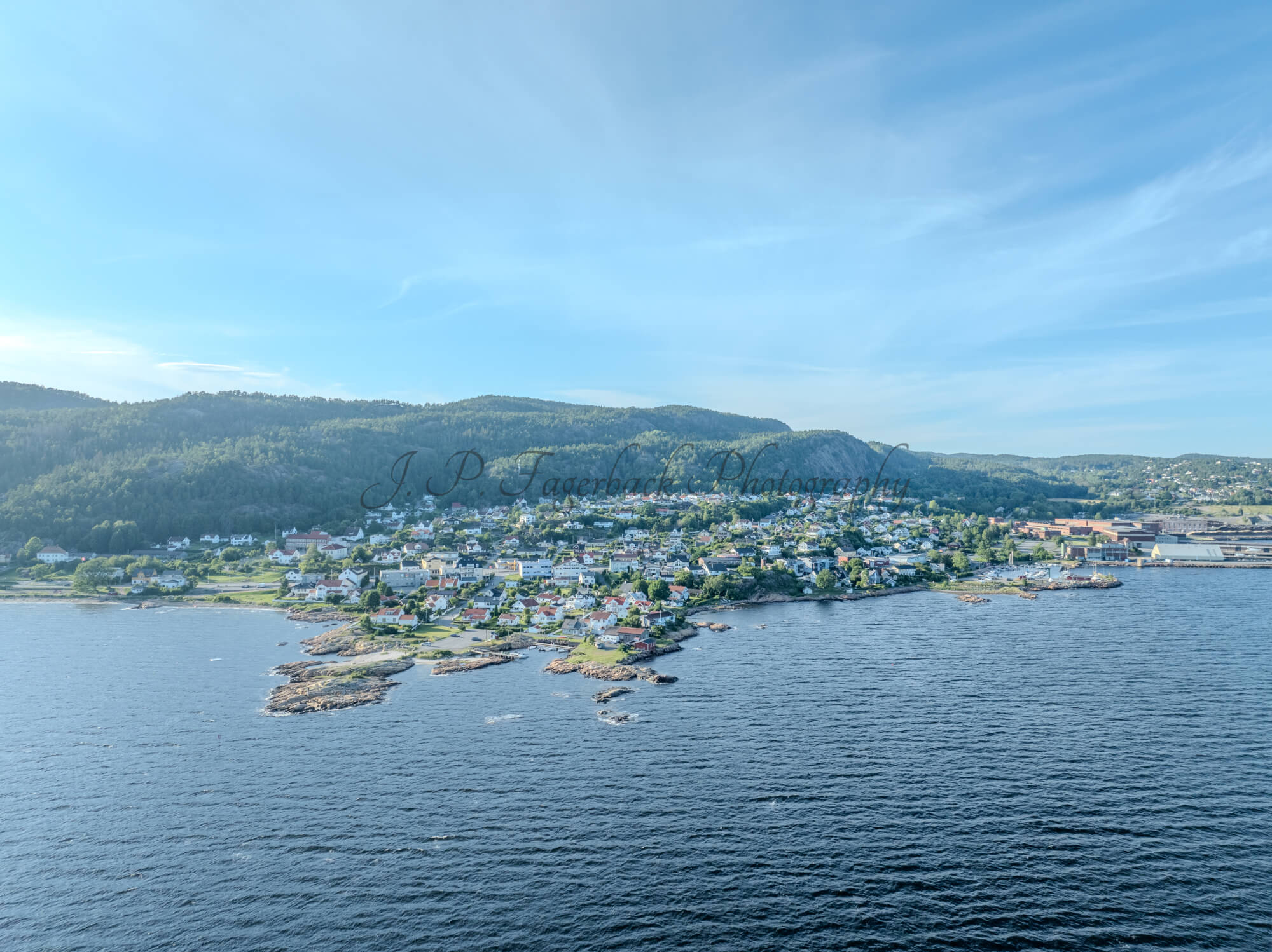 Houses of a town close to a body of water under an almost cloudless sky